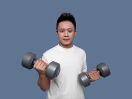 Man holding dumbbells in both hands isolated on plain background. photo