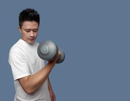 Young man doing exercises using dumbbells isolated on plain background photo