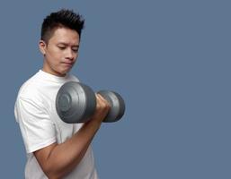 Young man doing exercises using dumbbells isolated on plain background photo