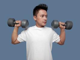 Young man doing the movement of lifting or biceps curl with dumbbells in both hands photo