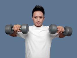 Young man is exercising using dumbbells in both hands photo