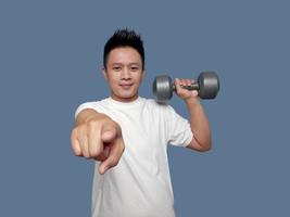 Man holding dumbbells and pointing forward isolated on plain background photo