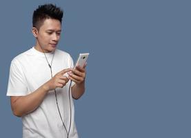 Man is looking and touching smartphone screen and using earphones photo