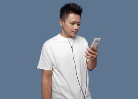 Man posing holding cell phone and using earphones looking at phone screen photo