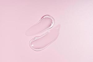 Glycerin gel texture. Transparent serum smudges on pink background. Liquid gel moisturizer with bubbles macro photo