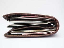 brown leather wallet full of credit cards and red bank notes on white background photo