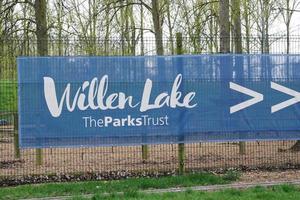 Low Angle View of Willen Lake Park with Local and Tourist Public Enjoying the Beauty of Lake and Park by Walking Around with Their Families. Footage Was Captured on 09-April-2023 at Milton Keynes UK photo