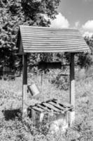 Old well with iron bucket on long forged chain for clean drinking water photo