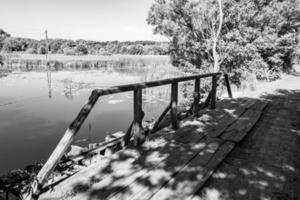 Beautifully standing old wooden bridge over river in light background photo