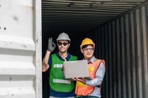 Team Engineer and worker wear safety uniform check control loading freight cargo container use computer laptop at commercial dock warehouse,transportation import,export logistic industrial service photo