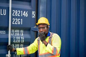 Worker man in protective safety jumpsuit uniform with yellow hardhat and use  Walkie Talkie check container at cargo shipping warehouse. transportation import,export logistic industrial service photo
