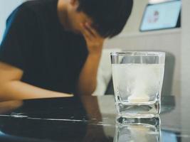 water soluble effervescent tablets Anti-flatulence pills, headache relief, multivitamin. Blurred background, man having headache from work. photo