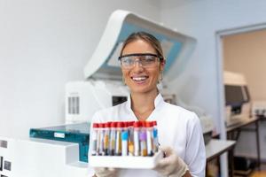 Blood test tubes. Female scientist examining blood test tubes at her laboratory dna testing analysis profession specialist clinician experienced medicine healthcare doctor photo