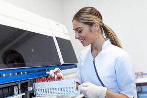 Portrait of a young female laboratory assistant making analysis with test tubes and analyzer machines sitting at the modern laboratory photo