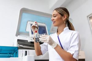 Lab tech loading samples into a chemistry analyzer. female lab tech loading specimen for coagulation test analysis photo