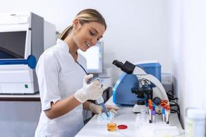 Closeup portrait, scientist pipetting from 50 mL conical tube with blue liquid solution, performing laboratory experiments, isolated lab . Forensics, genetics, microbiology, biochemistry photo
