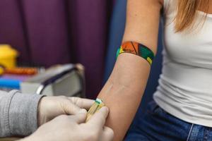 Preparation for blood test with pretty young woman by female doctor medical uniform on the table in white bright room. Nurse pierces the patient's arm vein with needle blank tube photo