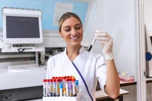 Technician holding blood tube test in the research laboratory. Coronavirus testing. Doctor taking a blood sample tube from a rack in the lab photo