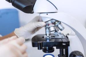 joven científico mirando mediante un microscopio en un laboratorio. joven científico haciendo algunos investigación. foto