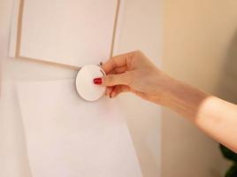 Female hand attaching pieces of white paper to the magnetic board for remind the important notice. photo