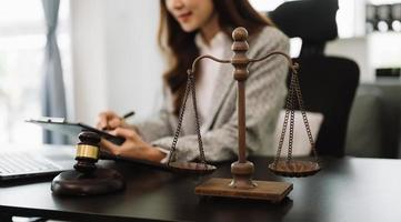 justice and law concept.law theme  wooden desk, books, balance. Male judge in a courtroom the gavel,working with digital tablet computer on table photo