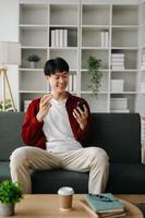 Young attractive Asian man smiling thinking planning writing in notebook, tablet and laptop working from home  at home office photo