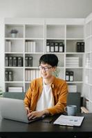 Handsome Asian business woman typing laptop and tablet Placed at the table at the modern office photo