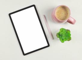 flat lay of digital tablet with blank white screen,  pink stylus pen, pink cup of coffee,  and plant pot  isolated on white background. photo