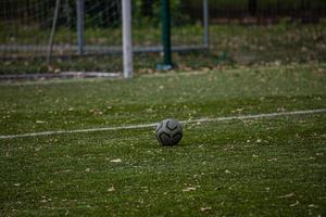 football lying on green artificial turf with autumn leaves photo