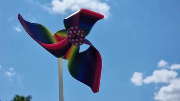 Pinwheel against the blue sky with clouds. Rainbow windmill. video