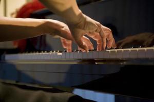 close-up on the hands of a woman playing the piano with music keys photo