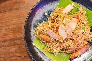 Mama drunken noodles. Noodles spicy in the bowl with ingredients on wooden background. photo