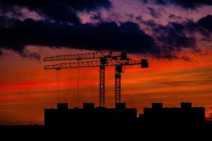 pintoresco paisaje con puesta de sol con construcción grúas en el horizonte foto