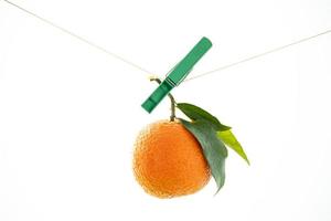 orange mandarin  with a green leaf hanging on a string on a white background photo