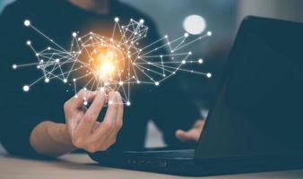 Businessman holding a bright light bulb, creativity with light bulbs and energy power, hand of a man with a light bulb and line light icon and using a notebook computer, technology innovation idea photo