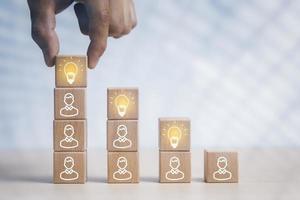 Wooden cube block human tower with light bulb icon on white background, Conceptual of creative idea and innovation, New business idea,Creative and new idea, brainstorming creative idea and innovation. photo