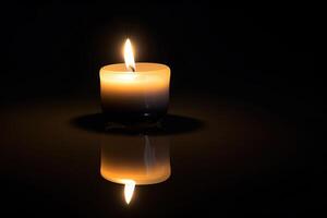 a candle is lit in the dark conveying memorial death and hope with copy space. photo