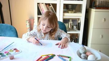 klein meisje zittend Bij tafel tekening Aan papier 4k video