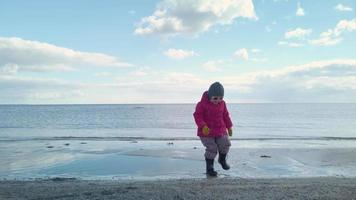 klein Mädchen Springen im flach Wasser im das Strand video