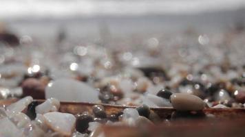 cerca arriba macro vídeo de piedras y guijarros consiguiendo cubierto como el marea viene en video