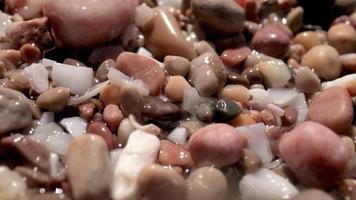 Close up macro video of stones and pebbles getting covered as the tide comes in
