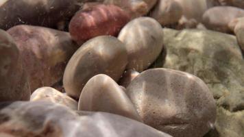 Close up macro video of stones and pebbles getting covered as the tide comes in