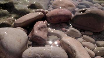 Close up macro video of stones and pebbles getting covered as the tide comes in