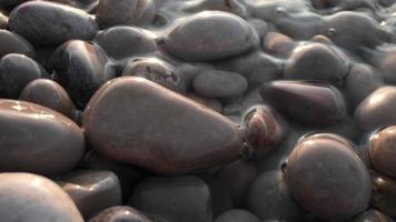 Close up macro video of stones and pebbles getting covered as the tide comes in