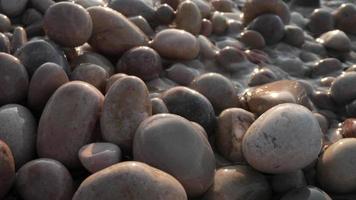 Close up macro video of stones and pebbles getting covered as the tide comes in