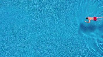 Aerial view of man in red shorts swims in the pool video