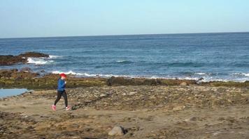 Woman runs along the stony shore of the ocean. Healthy active lifestyle video