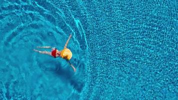 Aussicht von das oben wie ein Frau im ein rot Badeanzug Lügen auf ihr zurück im das Schwimmbad. entspannend Konzept video