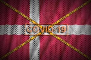 Denmark flag and Covid-19 stamp with orange quarantine border tape cross. Coronavirus or 2019-nCov virus concept photo