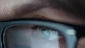 Woman in glasses looking on the monitor and surfing Internet. The monitor screen is reflected in the glasses video